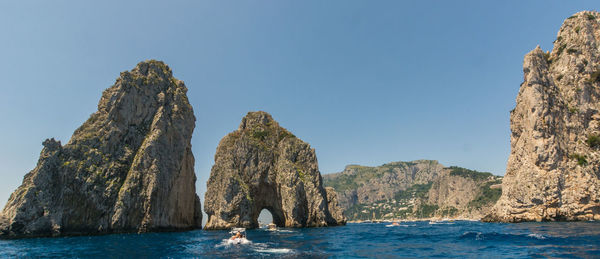 Scenic view of sea and rocks against clear blue sky