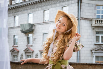 Little girl in dress and hat posing on the balcony