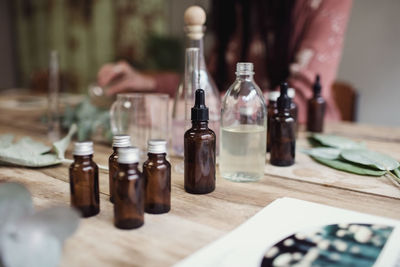 Midsection of female entrepreneur preparing perfume at table in workshop