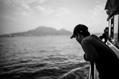 Man standing on boat at sea against sky