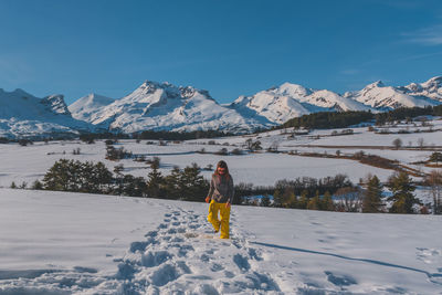 Rear view of woman walking on snow covered mountains