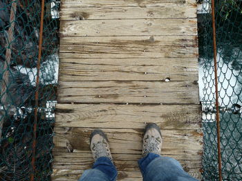 Low section of person standing on wooden fence