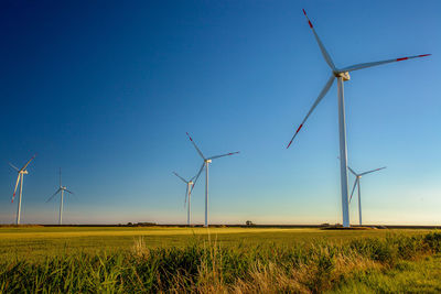 Wind turbines on field against clear sky