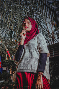 Portrait of young woman wearing hijab standing by tree