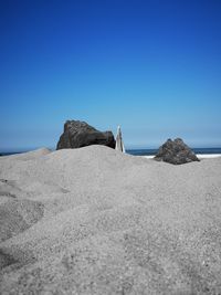 Surface level of rocks on beach against clear blue sky