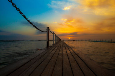 Pier over sea against sky during sunset