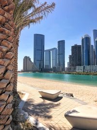 Modern buildings by swimming pool against sky in city