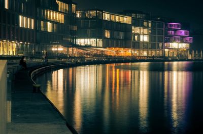 Illuminated buildings by river at night