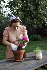 Girl holding flower pot on table