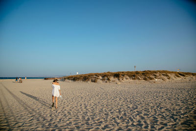 Rear view of woman walking on sandy beach