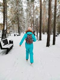 A girl in a sports jumpsuit walks in the park in winter.