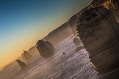 Rock formation on beach against sky during sunset