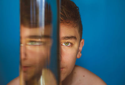Portrait of a boy looking through water filled glass.