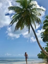 Rear view of woman standing at beach against sky