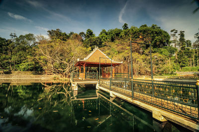 Bridge over lake by trees against sky