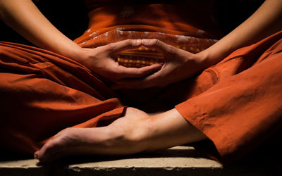 Low section of person meditating in darkroom