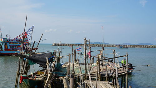 Fishing boats moored at harbor against sky