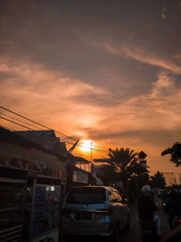 Cars on street against orange sky