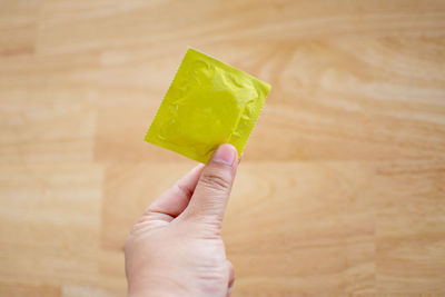 Close-up of man holding condom on table
