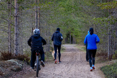 Rear view of people running on dirt road