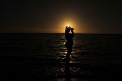 Silhouette man standing on beach against sky during sunset