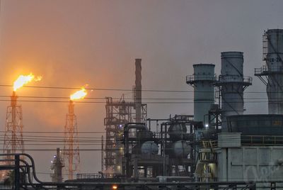 Illuminated factory against sky during sunset