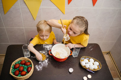 Sister and brother cook in the kitchen, knead the dough, easter holiday