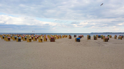 People on beach against cloudy sky