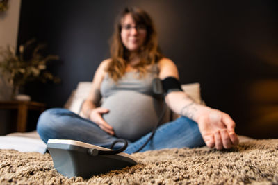 Pregnant woman using blood pressure gauge at home