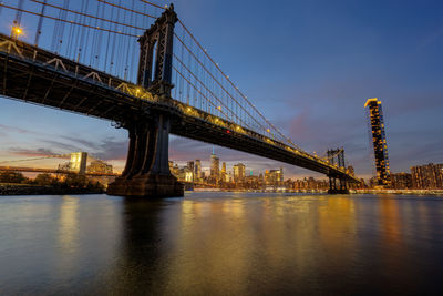 Illuminated bridge over river against sky at night