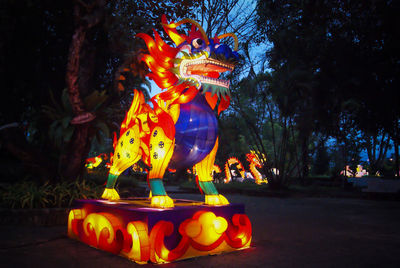Illuminated statue against trees at night