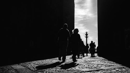 Silhouette people walking on sidewalk in city