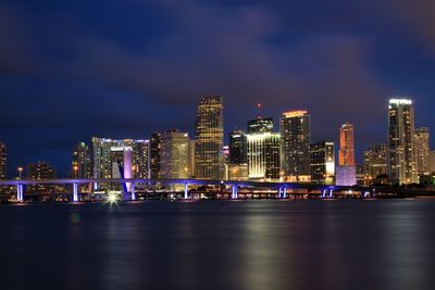 Illuminated modern buildings in city against sky at night