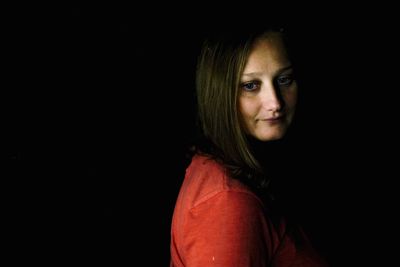 Portrait of young woman against black background