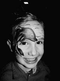 Portrait of smiling boy against black background