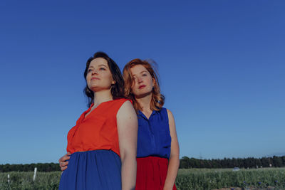 Women standing in field against clear blue sky