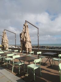 Empty chairs and tables against sky