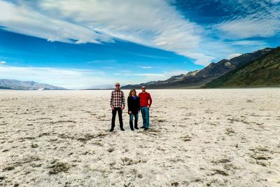 Full length of friends standing on desert against sky