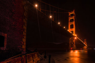 Low angle view of illuminated bridge over bay at night