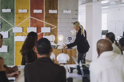 Female professor explaining students over social robot in innovation lab