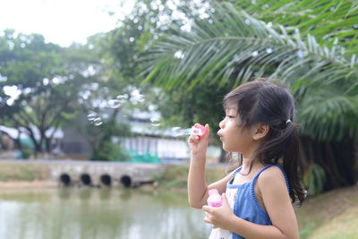 Girl blowing bubbles by pond