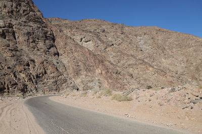 Road amidst desert against clear sky