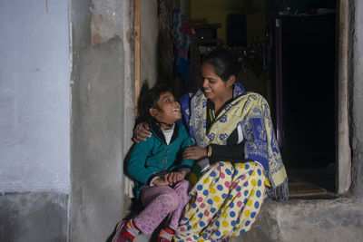 Happy indian mother and daughter sitting at outside her house