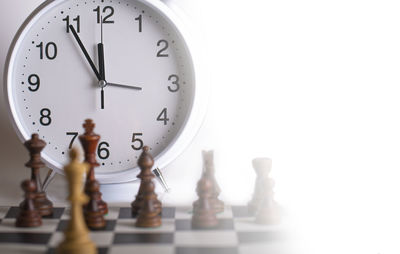 Clock and chess pieces on a chessboard. as background. 