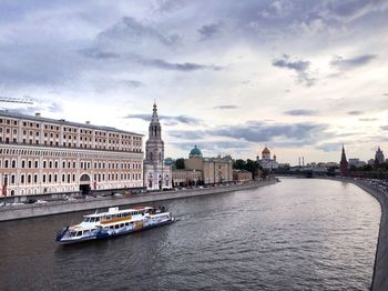 View of buildings at waterfront against cloudy sky