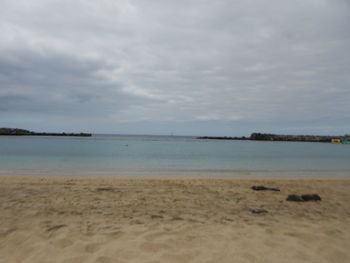 Scenic view of beach against cloudy sky