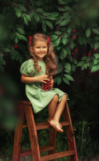 Portrait of smiling girl sitting and eating cherries