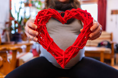 Close-up of woman holding heart shape on table