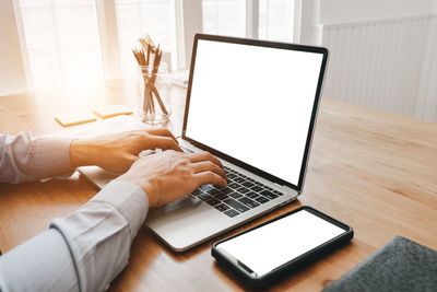 Midsection of man using laptop on table