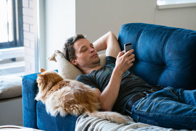 Rear view of man lying down on sofa